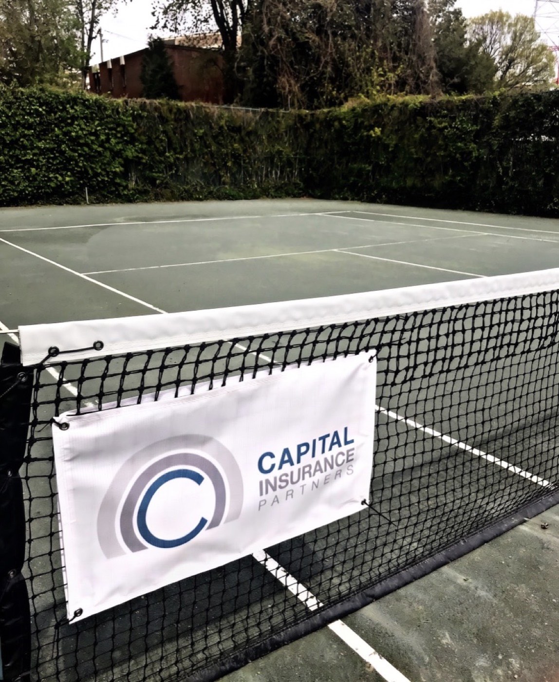 A Capital Insurance Partners banner on the net of a tennis court
